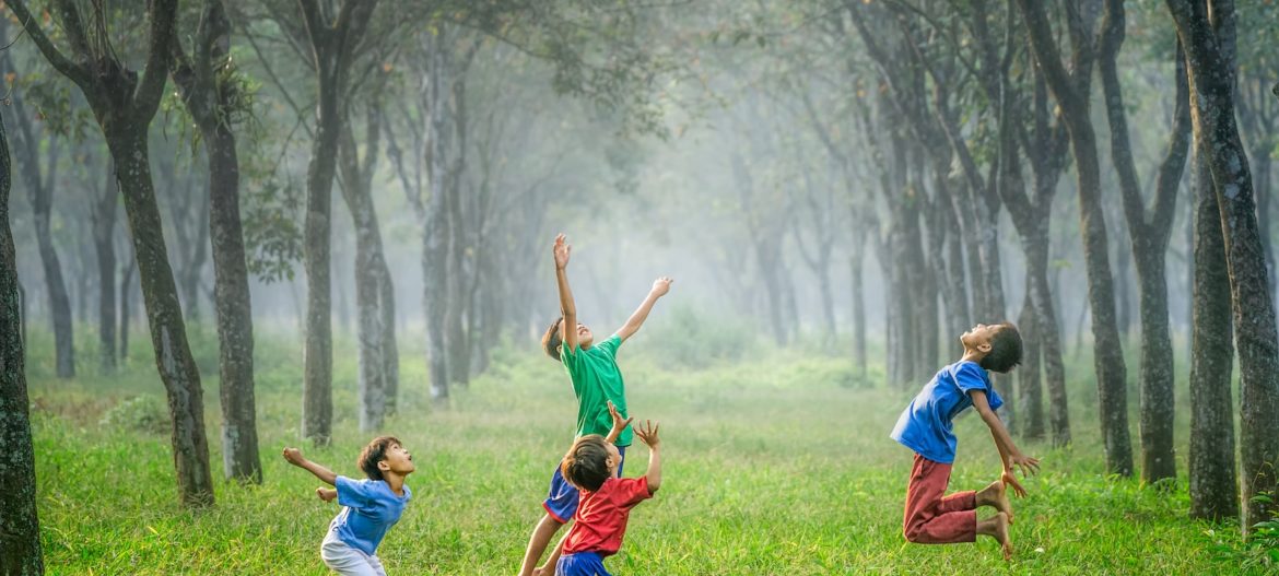 four boy playing ball on green grass